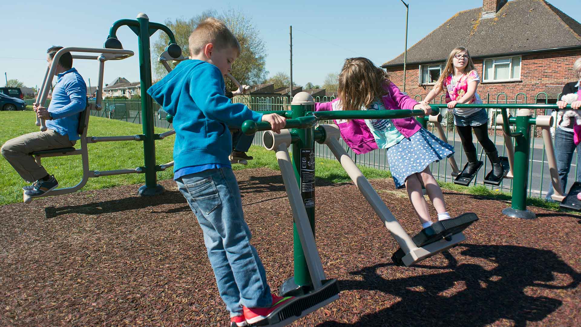 Children using outdoor fitness equipment on a play area