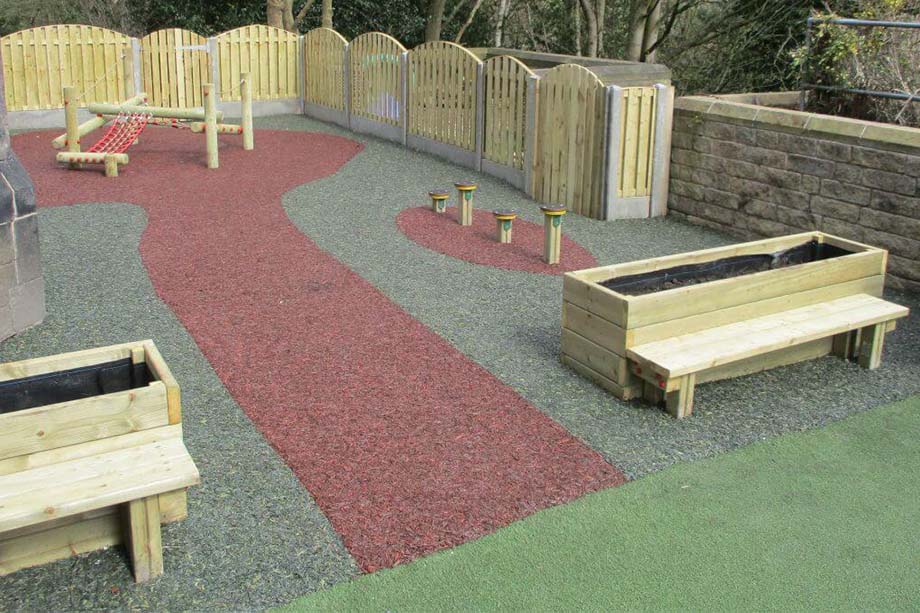 Shelters, seating and staging in a school courtyard with red pathway surfacing
