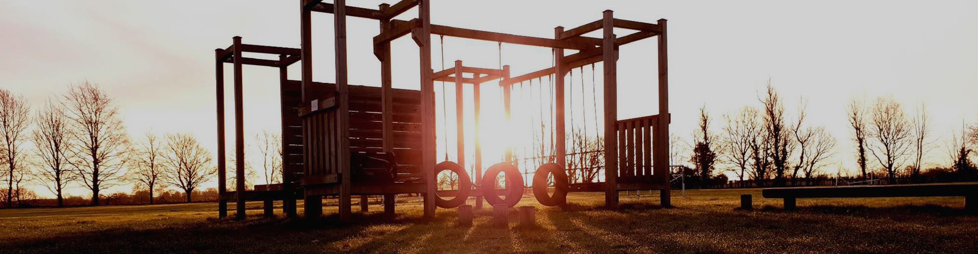 A timber climbing and adventure frame silhouetted against a low sun