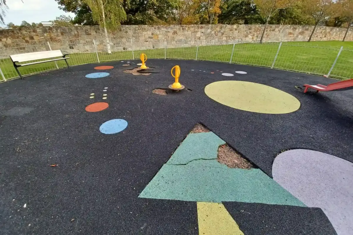 Play park with broken multicoloured wetpour rubber flooring