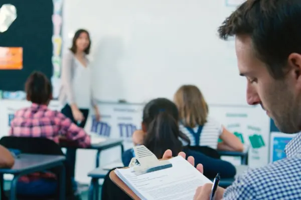 Male inspecting female teacher during class