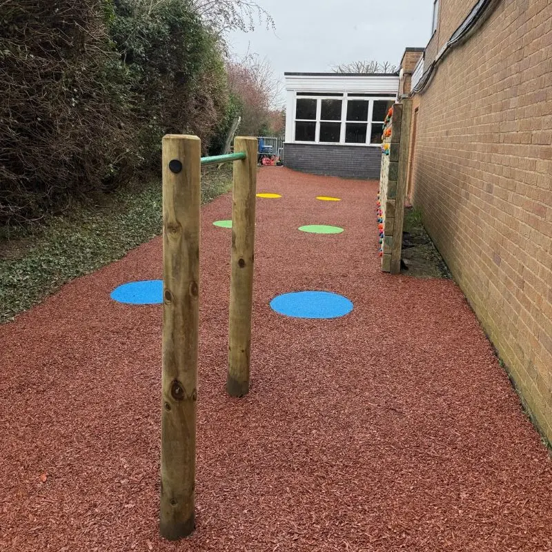 Rubber mulch area at a school with a chin up bar
