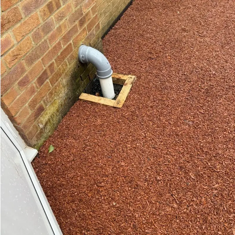 Boxed drain pipe surrounded with rubber mulch