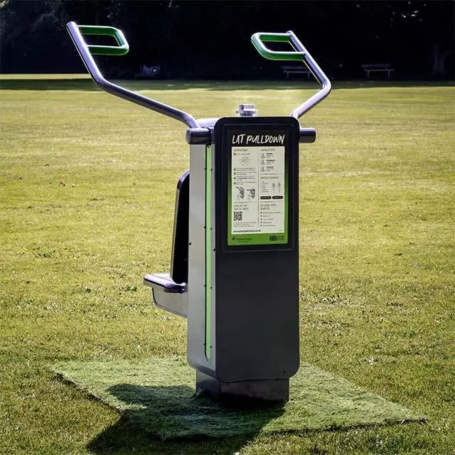 Outdoor exercise equipment on a grassy field, labeled "Lat Pulldown." It features metal handles, a display panel with instructions, and has a modern design.